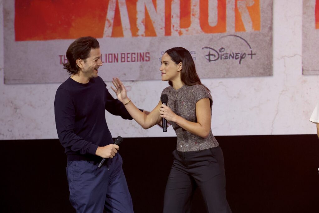 ANAHEIM, CALIFORNIA - SEPTEMBER 10: (L-R) Diego Luna and Adria Arjona speak onstage during D23 Expo 2022 at Anaheim Convention Center in Anaheim, California on September 10, 2022. (Photo by Jesse Grant/Getty Images for Disney)